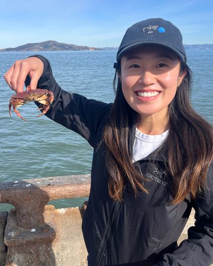 Danielle on a pier in San Francisco, holding a very small crab